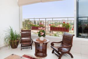 卡法萨巴法萨巴景公寓 的一间设有两把椅子和一张带鲜花的窗户桌子的房间