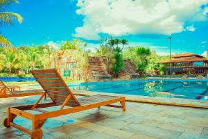 卡达斯诺瓦斯Ecologic Ville Resort - Oficial的一张木椅,位于游泳池旁