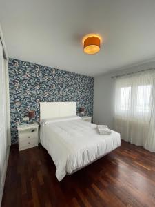 波尔托辛Hostal Portofino的卧室配有一张白色大床和一堵墙