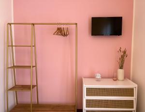 阿巴迪亚拉里亚纳Miss Scola Pastry Rooms - Lake Como的一间设有粉红色墙壁、书架和电视的客房