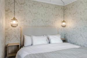 恩舍尔兹维克Nyrenoverat gårdshus på havstomt med hög standard的一间卧室配有一张白色床和两盏吊灯