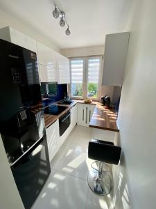 格利维采Apartament Glamour Work&Relax, obok ARENY Gliwice, FV的厨房配有白色橱柜和黑色冰箱。