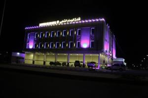 Al Ḩanākīyahفندق الوسام الذهبي的一座灯光建筑,晚上外面停有汽车