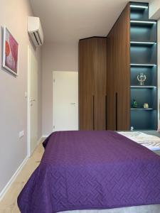地拉那Lovely 1-bedroom Condo in Tirana WiFi-Netflix-AC的一间卧室配有一张紫色的床和一个木制橱柜
