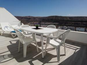 莫甘Puerto Rico apartamento 1 dormitorio wifi piscina的阳台上配有白色的桌椅