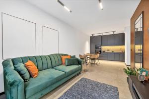 罗兹Luxury Copper Apartment的一间带绿色沙发的客厅和一间厨房
