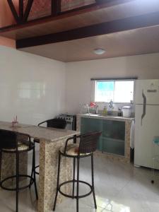 韦尔卡鲍Chalé Verde - Vale do Capão的厨房配有带椅子的柜台和冰箱。