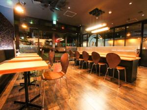 挂川市HOTEL LiVEMAX Kakegawa-Ekimae的一间带木桌椅的餐厅和一间酒吧