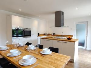 Orchard View - 4-Bed Home In Kempsford, Cotswolds的厨房配有木桌、盘子和酒杯