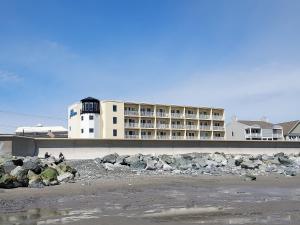 汉普顿OC North Beach ocean front condo with spectacular views的海滩上的一座建筑,前面有岩石