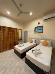 图杜Thoddoo Retreat Grand的酒店客房配有两张床和吊扇。