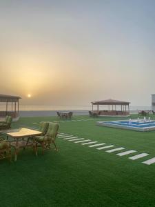 Ḩilf达纳阿尔卡勒酒店的绿地,带桌椅,大海