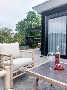奥德多普Luxe vakantiehuis Nova met zwembad的天井设有长凳和一张带葡萄酒玻璃的桌子。