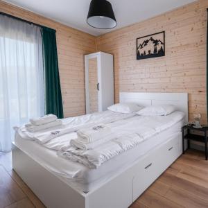 SablówkaJagodówka的一张白色大床,位于带木墙的房间