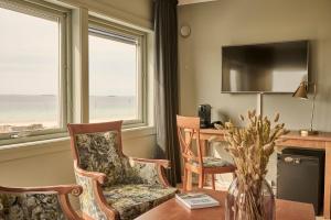 索拉索拉海滨酒店的客厅配有2把椅子、书桌和电视