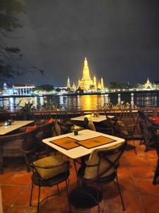 曼谷萨拉阿伦酒店的一间设有桌椅的餐厅,享有寺庙的景色