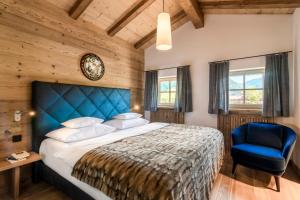 雷特温克尔Relais & Châteaux Gut Steinbach Hotel Chalets SPA的一间卧室配有一张大床和一张蓝色椅子
