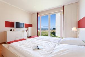 诺德奈Strandhotel Georgshöhe的卧室设有一张白色大床和一扇窗户。