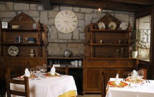 卡斯特洪德索斯比利牛斯山酒店的一间设有两张桌子和墙上一个时钟的餐厅