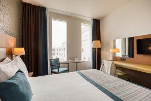 奥德纳尔德Leopold Hotel Oudenaarde的配有一张床、一张书桌和一扇窗户的酒店客房