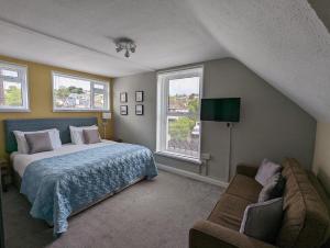 布里克瑟姆雷德兰兹旅馆的一间卧室配有一张床、一张沙发和两个窗户。