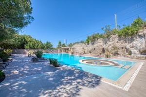 切什梅AEGEAN Apartments - Çeşme的一座带岩石墙的度假村内的游泳池