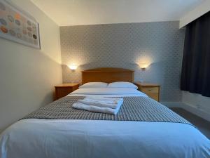 考文垂海兰斯酒店的一间卧室配有一张床,上面有两条毛巾