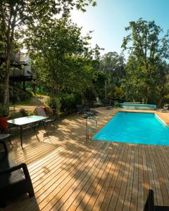 庞特维德拉Cabanas de Udra的木制甲板上的游泳池,配有桌椅