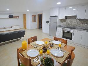 奥格罗夫半岛圣维森特Apartamentos Playa Area Grande的厨房配有带盘子和橙汁杯的桌子