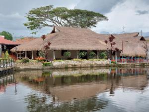 GarzónHotel Campestre San Joaquin的茅草屋顶的房子,靠近水体