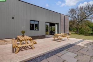 SnettertonFen Lane Lodge的一个带两张野餐桌的庭院和一座建筑