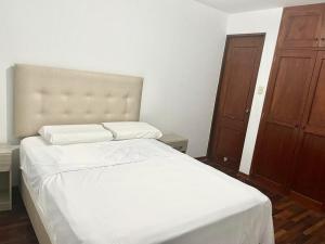 特鲁希略Apartamento en el Centro de Trujillo - Primer Piso的卧室配有白色的床和木门
