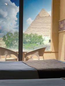 开罗Giza Pyramids View Inn的一间设有一张床的客房,一个金字塔穿过一个窗口