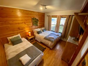普孔Hotel Andes Pucón的木制客房内的一间卧室配有两张床