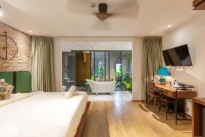 岘港Seaforest Hotel by Haviland的一间卧室配有一张床、一张书桌和一个浴缸