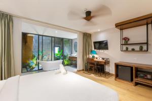 岘港Seaforest Hotel by Haviland的一间卧室配有一张大床、浴缸和一张书桌
