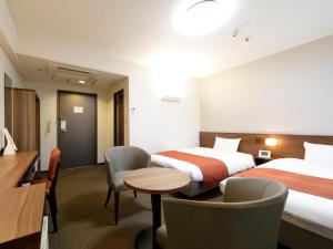 东京东京Inn的酒店客房带两张床和一张桌子以及椅子。