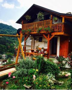 亚伊采Privatni smještaj Kurtalija的庭院里一座带甲板和鲜花的房子