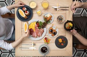 名古屋名古屋JR门楼酒店的一群人坐在桌子旁,一边吃早餐