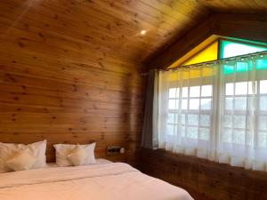 西姆拉Sugar Cube Retreat的一间卧室设有木墙、一张床和一个窗户