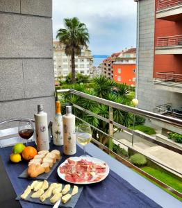 桑亨霍Apartamento turístico en Sanxenxo的阳台上的桌子上摆放着食物和葡萄酒