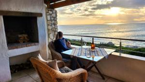干斯拜克雷西海滨旅馆的坐在俯瞰大海的阳台桌子上的女人