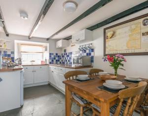 以撒港Cloam Cottage的厨房配有带椅子的木桌和桌子。