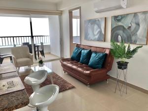卡塔赫纳apartamento en bocagrande的客厅配有棕色真皮沙发和蓝色枕头。