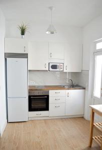 费罗尔Apartamento en centro de Ferrol的厨房配有白色橱柜、水槽和微波炉
