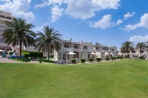 艾恩Radisson Blu Hotel & Resort, Al Ain的棕榈树和绿色庭院的度假村