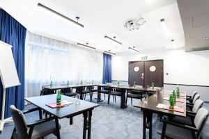罗兹罗兹Qubus酒店的一间会议室,配有桌椅和大窗户