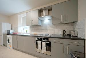 哈德斯菲尔德Alpha Lofts, Huddersfield的厨房配有白色橱柜和炉灶烤箱。