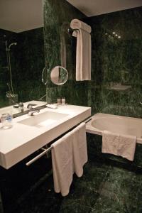 马德里Aravaca Village Hotel的浴室配有盥洗盆、浴缸和毛巾