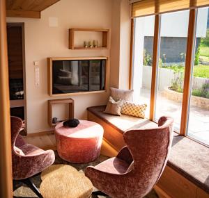 菲尔斯Alpenchalet Vils Tirol的客厅配有椅子、桌子和电视